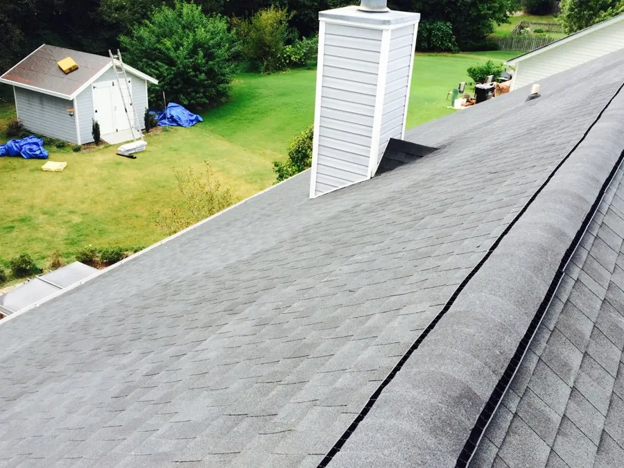 New shingles along a ridge line beside a sided chimney chase